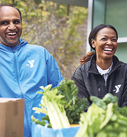 Two Y volunteers bagging vegetables and laughing