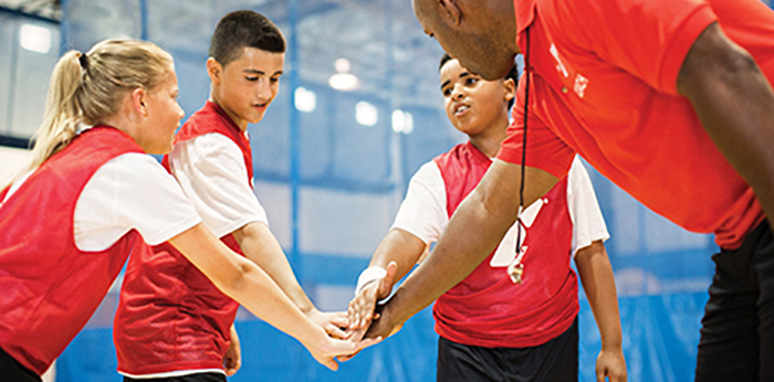 Teammates and sports coach with their hands in