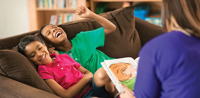 Kids laughing as an adult reads them a book