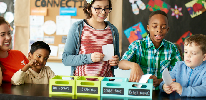 Young and older kids place paper in different color boxes